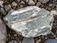 Hellgrauer Stein mit weißen Anteilen durchzogen von Riefen